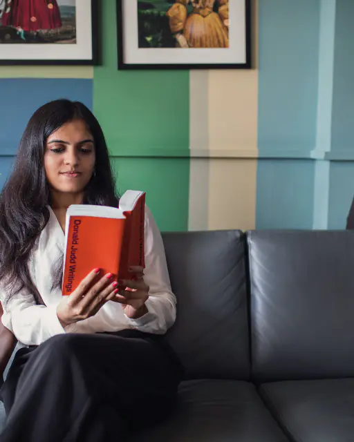 A woman relaxing on a sofa with a book